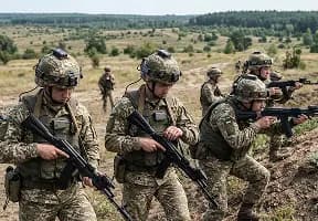 Група екіпірованих військових проводить тактичне тренування з лазерною зброєю на відкритій місцевості в умовах лісового ландшафту