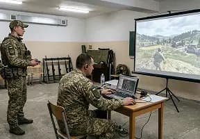 Військовий за ноутбуком моделює бойовий сценарій на великому екрані для відпрацювання тактики у віртуальному середовищі